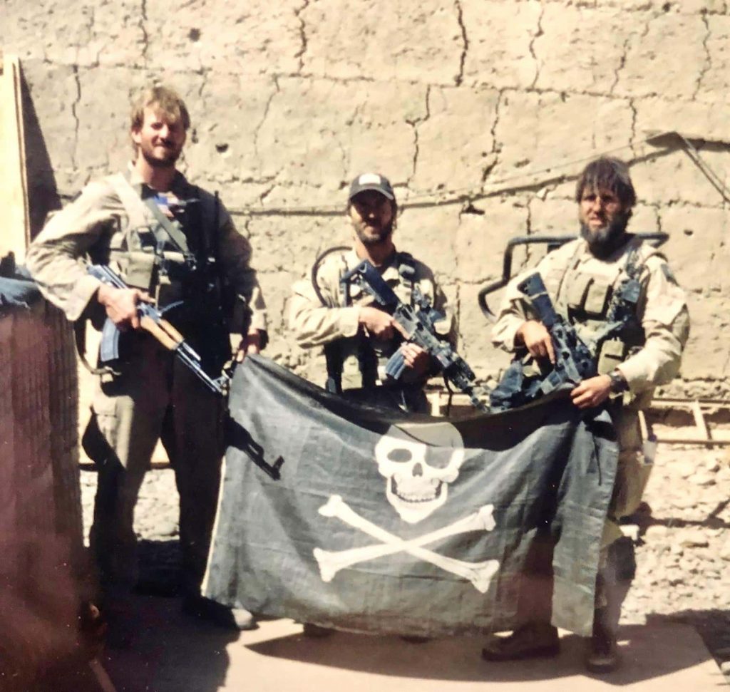 3 Seal Team 6 operators posing with a Blue Squadron flag.