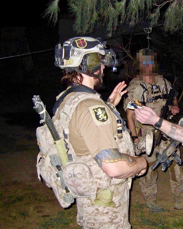 One DEVGRU operator shoves a power bar in another's face while a third one looks on.