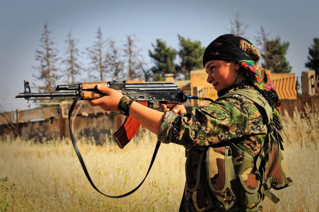 Female Kurdish YPG fighter aiming a rifle.
