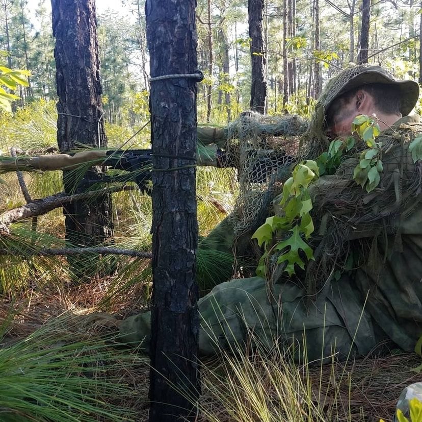 US Sniper wearing camo in the woods.